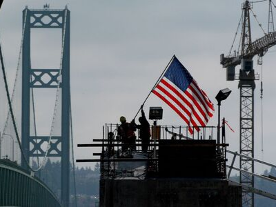 construction workers hoist an American flag on a project site